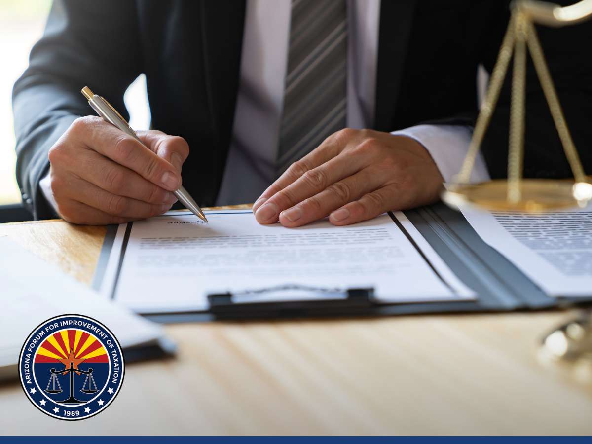 Business professional reviewing documents for the Employee Retention Credit program, Arizona Forum for Improvement of Taxation emblem visible